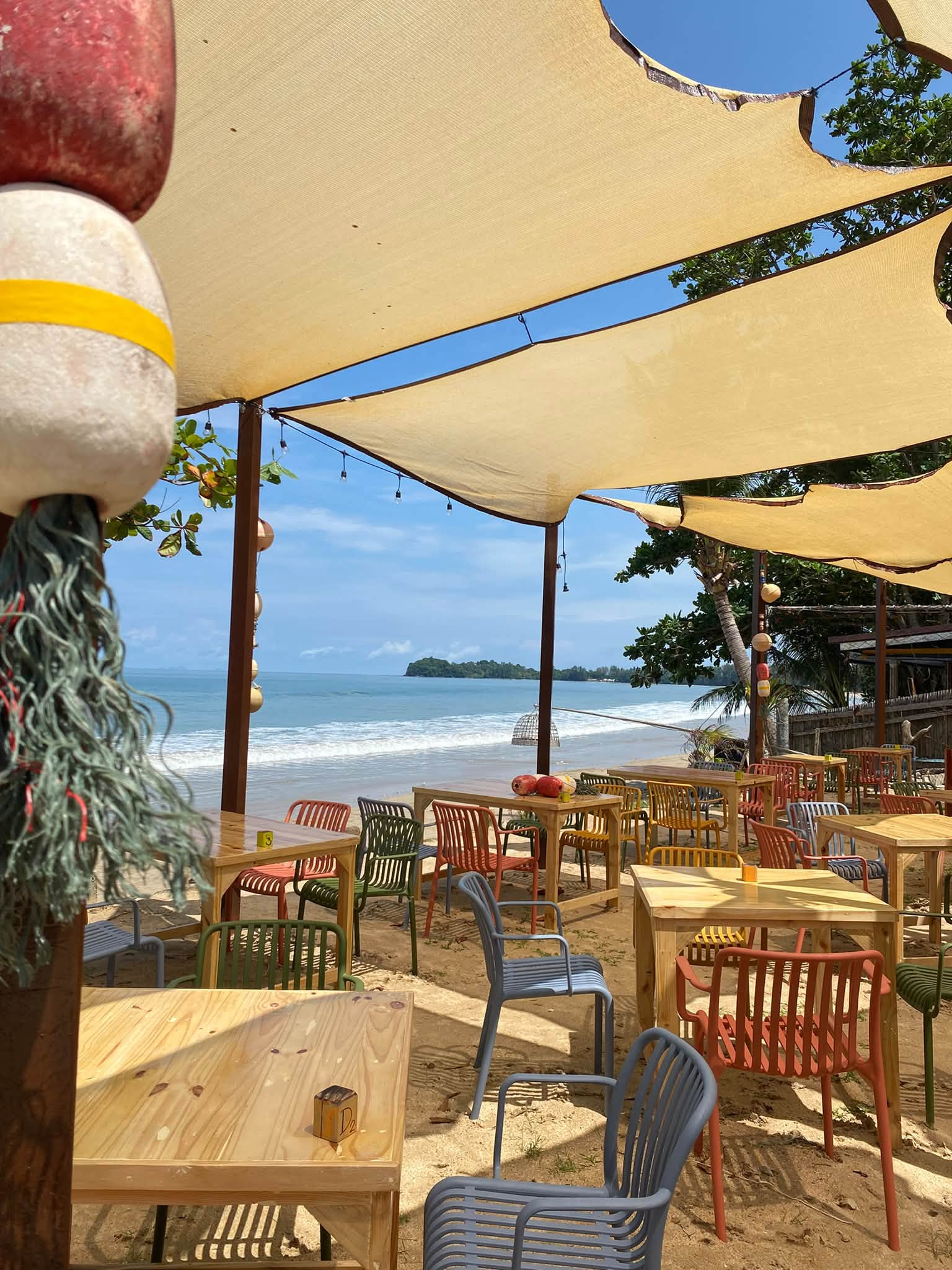 Colourful chairs and shaded tables directly on Klong Dao Beach at Tienhomm